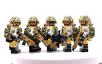 Five toy soldier minifigures in tan and green camouflage uniforms holding rifles, arranged side by side on a white surface against a white background. Fabled Figs