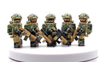Five military minifigures in camouflage uniforms and helmets, each holding a black and tan rifle, standing on a white circular platform against a white background.
