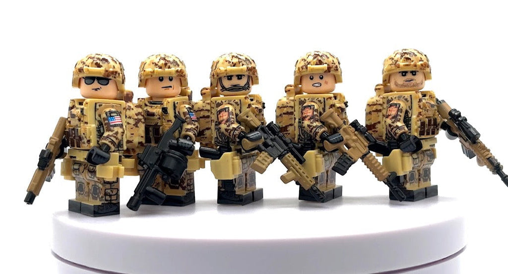 Five toy soldier minifigures in desert camouflage uniforms and helmets, each holding a black rifle, displayed on a white circular pedestal against a white background. Fabled Figs