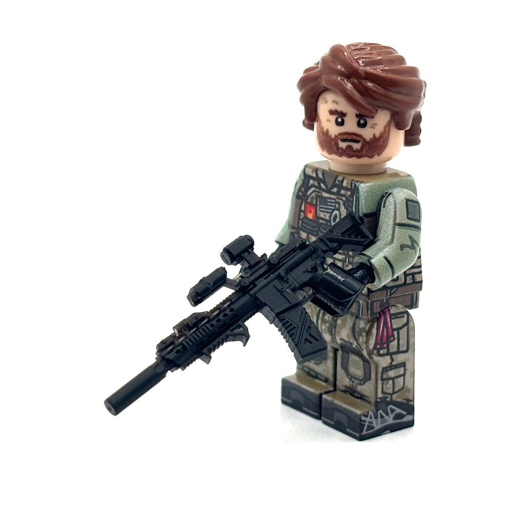 A custom-built military minifigure with brown hair and beard, wearing a green tactical combat jacket and camouflage pants, holding a black rifle, set against a plain white background.